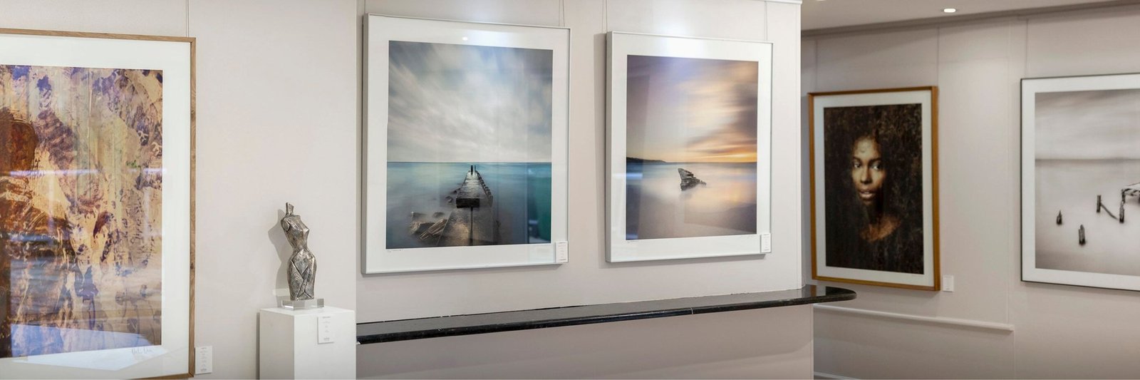 Framed photographs and paintings on the walls of Osner Gallery in Hout Bay